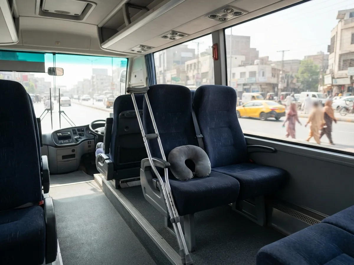 The front row seats of a clean air conditioned intercity coach with generous leg room, a pair of aluminium elbow crutches resting against the window and a small travel pillow on the seat, photographed from the aisle. No people. Photograph taken in Karachi, Pakistan. Any person shown is Pakistani and well dressed, with the face out of frame. Natural daylight, realistic colours, documentary style. No text, no signage, no logos, no watermarks. 4:3 aspect ratio.